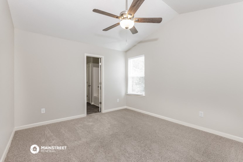 the spacious living room with ceiling fan and carpet