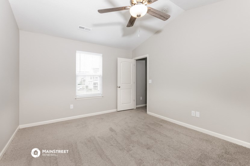 the spacious living room with ceiling fan and carpeting
