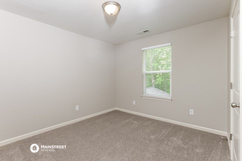 the bedroom of a manufactured home with carpet and a window