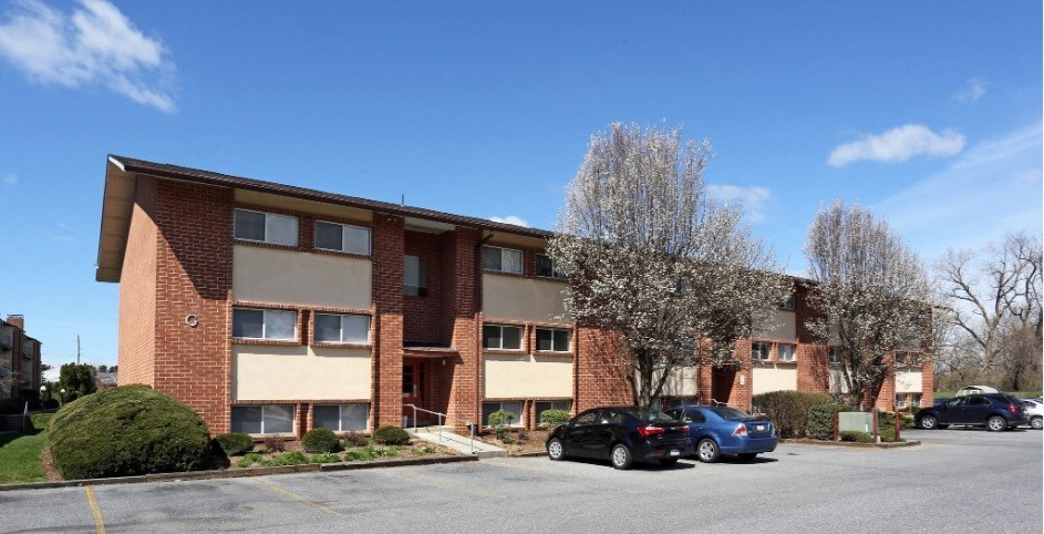 a brick apartment building with cars parked in a parking lot