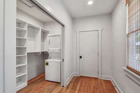 A white refrigerator is in a kitchen with wood floors.