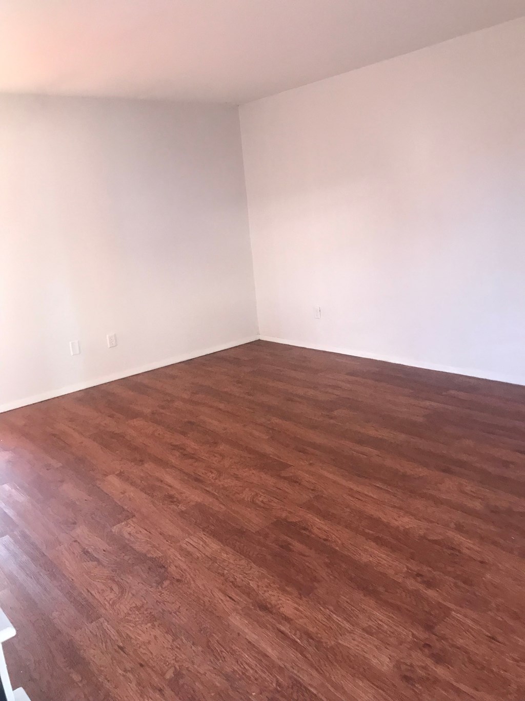 A room with wooden flooring and white walls.