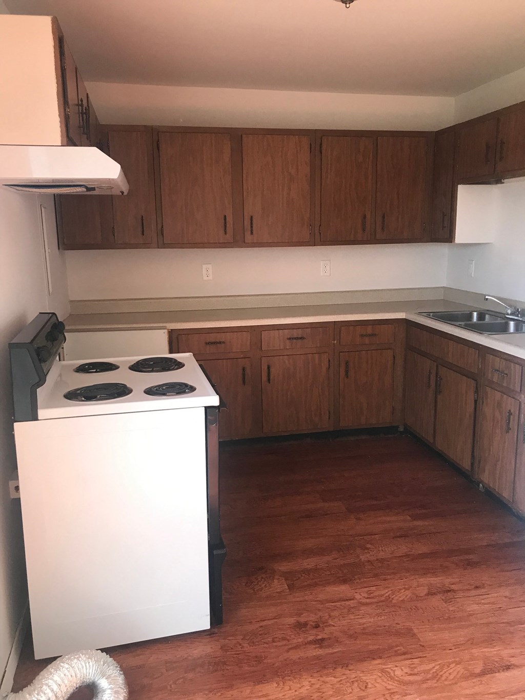 A kitchen with a white stove and wooden cabinets.