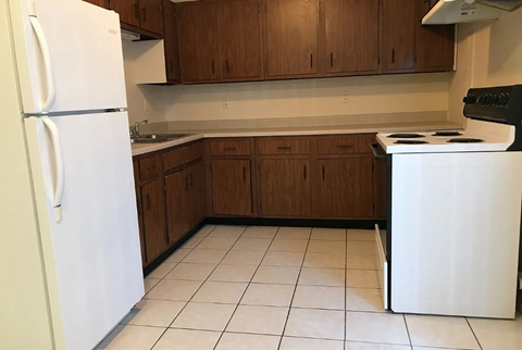 A white refrigerator stands in a kitchen with wooden cabinets.