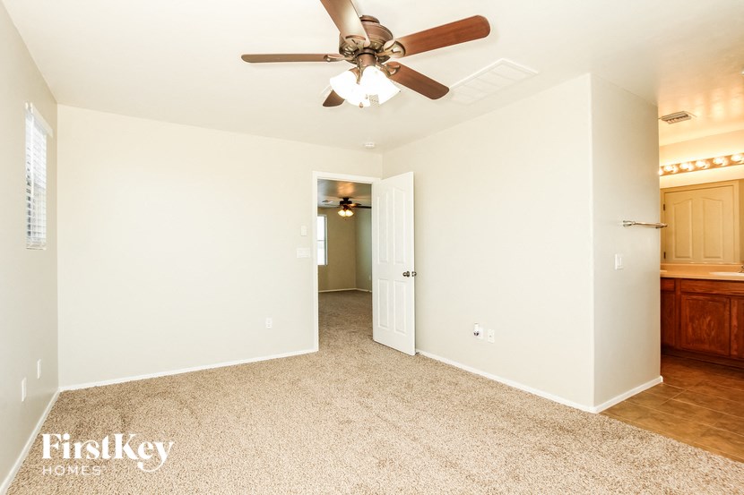 a living room with a ceiling fan and a hallway to a kitchen