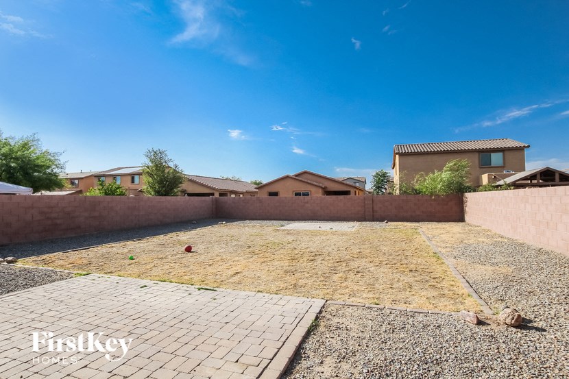 a backyard with gravel and a brick wall and a house in the background