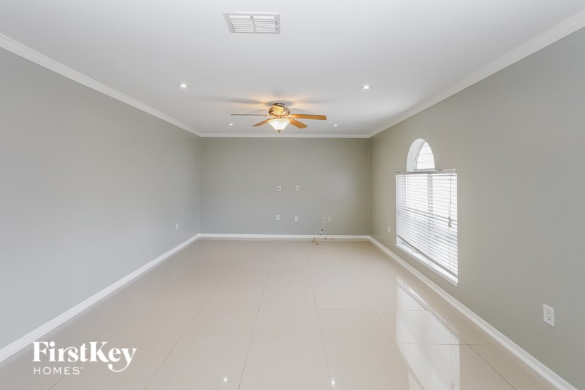 A spacious room with a ceiling fan and a window with blinds.