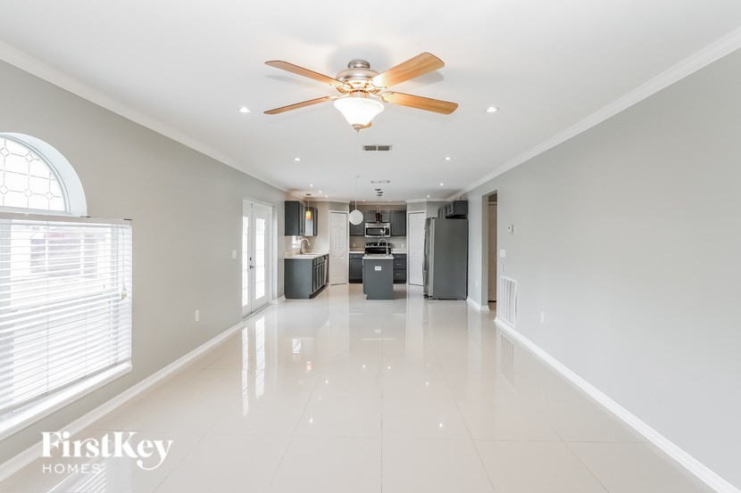 A spacious, empty room with a ceiling fan and a large window.