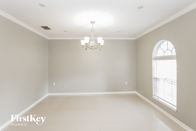 A large empty room with a chandelier and a window.