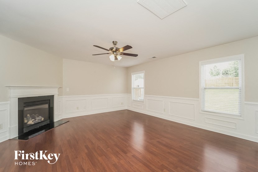 an empty living room with a fireplace and a ceiling fan
