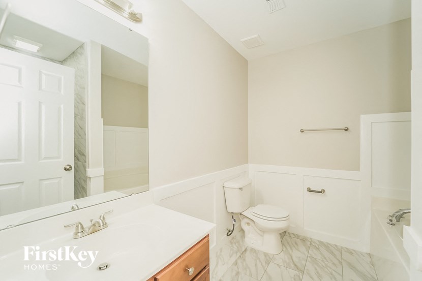 a white bathroom with a toilet and a mirror