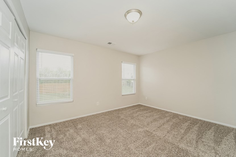 an empty room with carpet and two windows