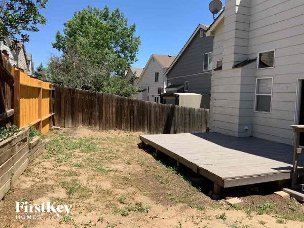 a backyard with a wooden deck and a fence