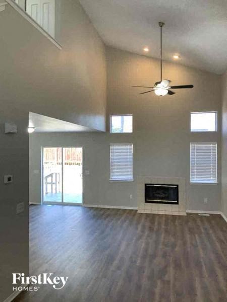 an empty living room with a ceiling fan and a fireplace