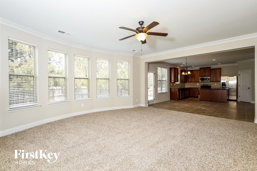 an empty living room with a ceiling fan and a kitchen
