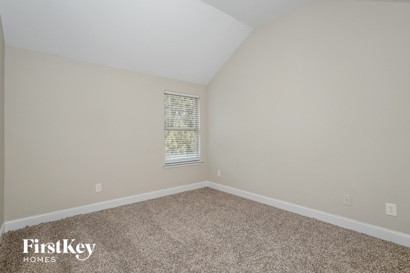 the upstairs bedroom has a carpeted floor and a window