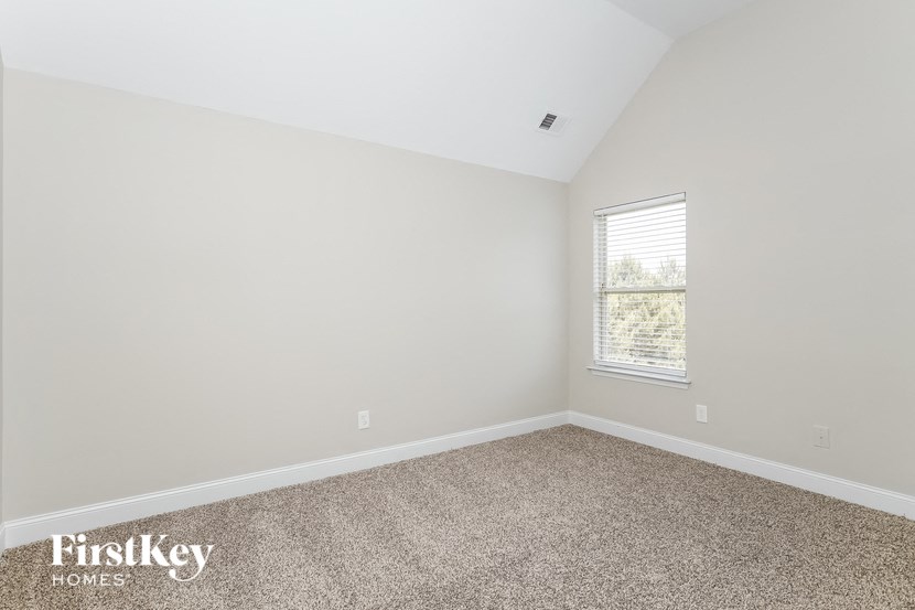 a bedroom with white walls and carpet and a window