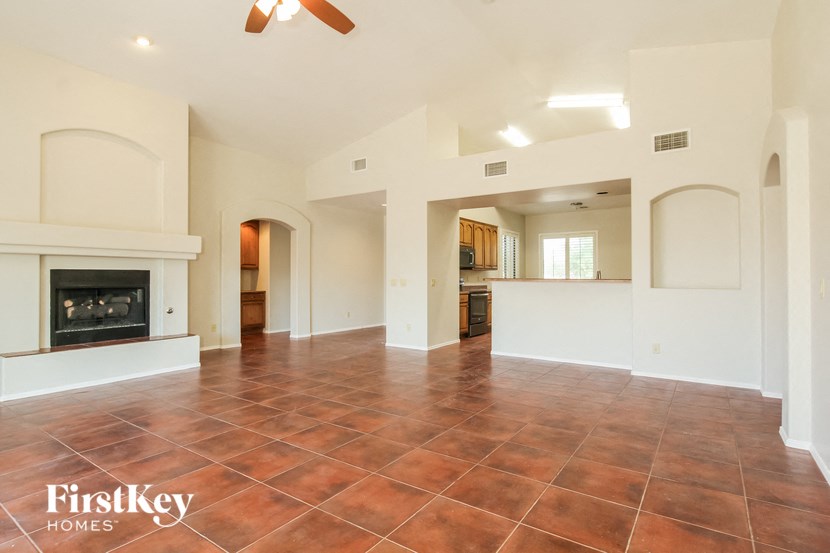 A spacious living room with a fireplace and a ceiling fan.
