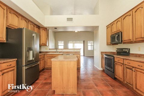 A kitchen with wooden cabinets and a black refrigerator.