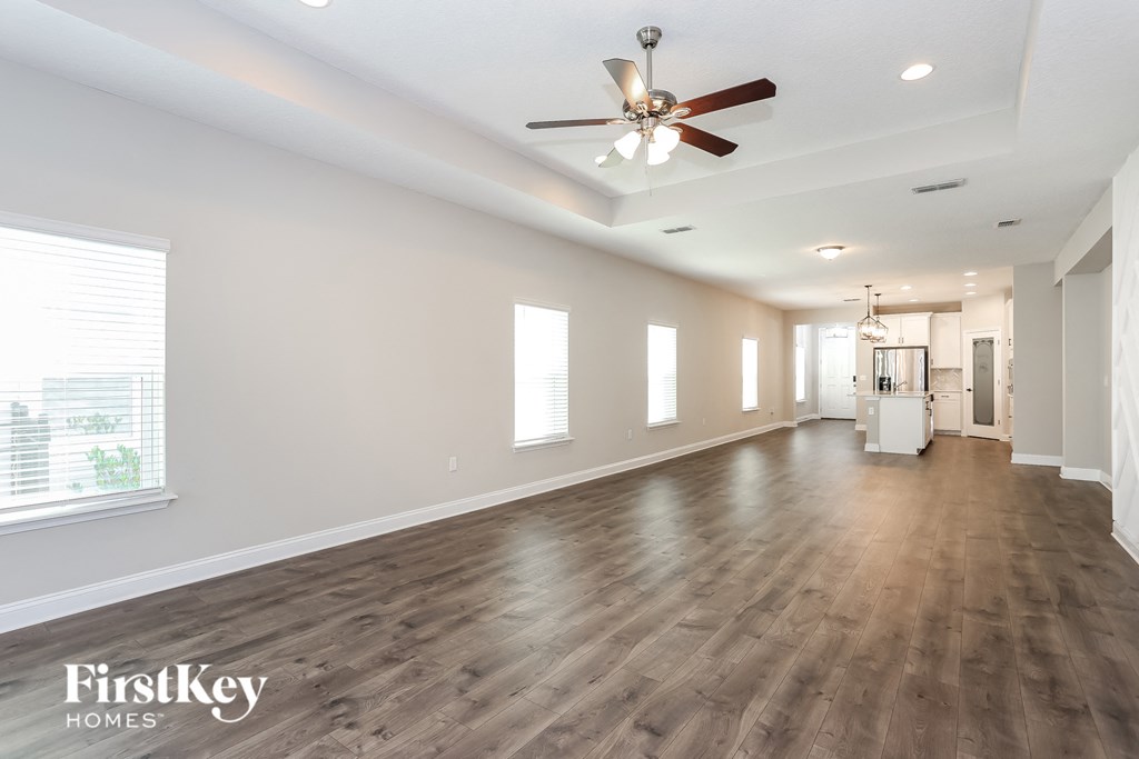 an empty living room with a ceiling fan and white walls