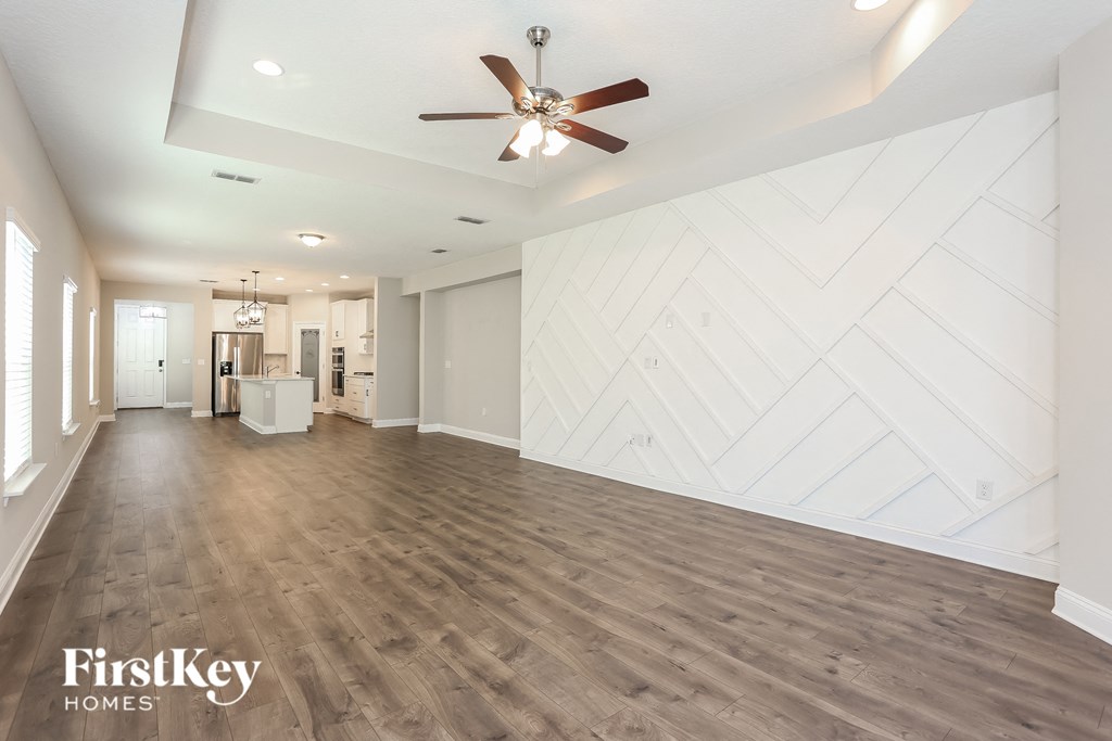 an empty living room with a white wall and a ceiling fan