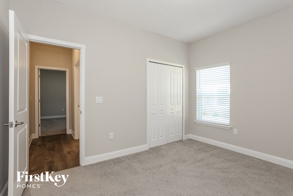 a bedroom with a door to a hallway and a closet