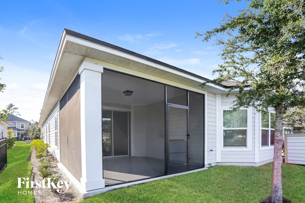 a small white house with a glass door and a lawn