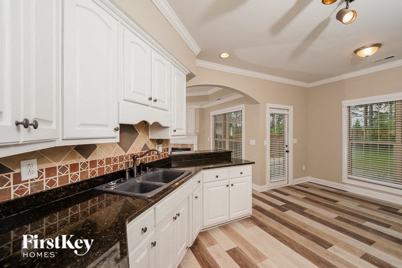 a kitchen with white cabinets and a black counter top