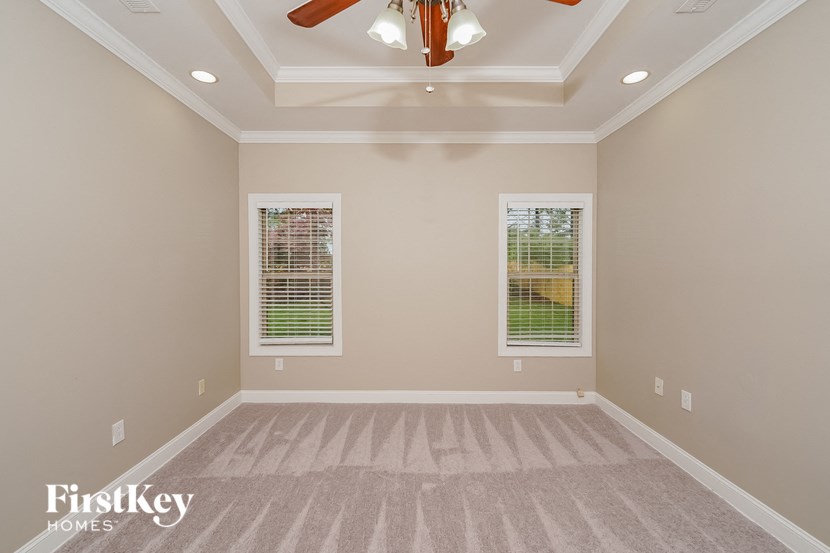 a empty living room with a ceiling fan and two windows
