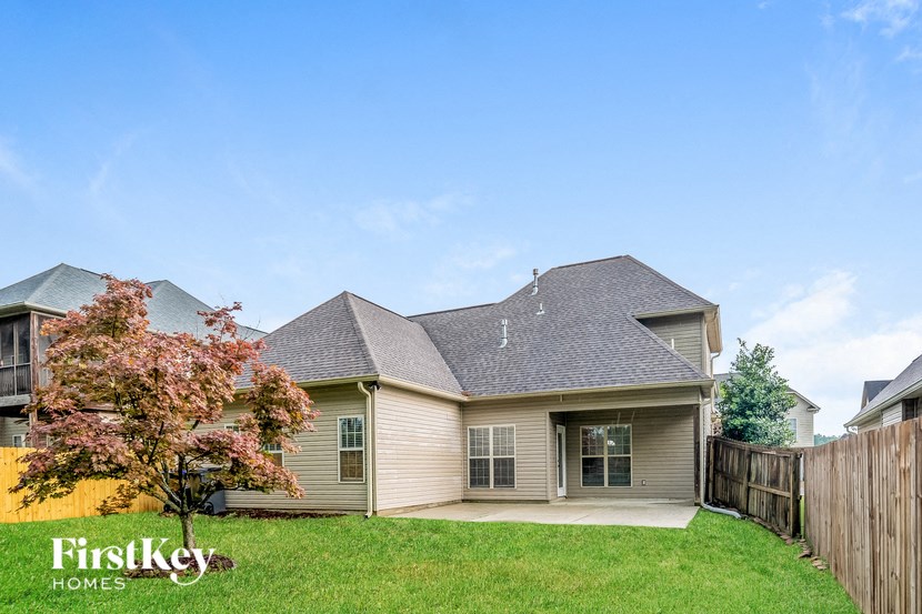 a tan house with a yard and a wooden fence