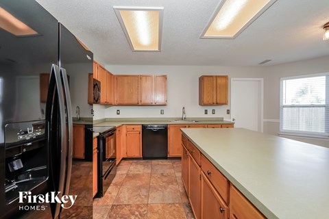 A kitchen with wooden cabinets and a black refrigerator.