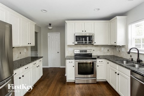 A kitchen with white cabinets and a stainless steel oven.