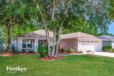 a house with a lawn and trees in front of it