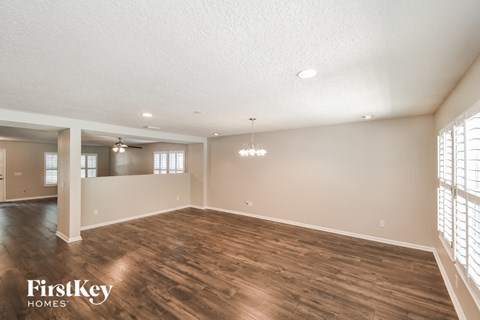 the spacious living room with wood flooring and white walls