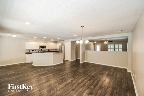 an open kitchen and living room with hardwood flooring and a kitchen counter top