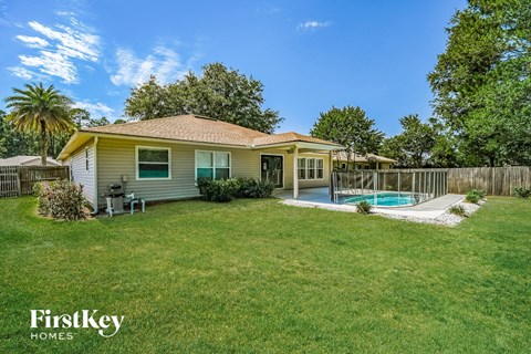 a backyard with a pool and a yellow house