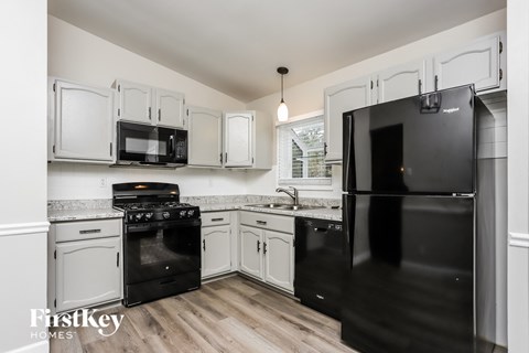 a kitchen with white cabinets and black appliances