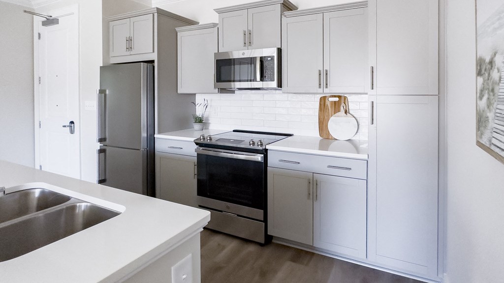 a white kitchen with stainless steel appliances and white cabinets