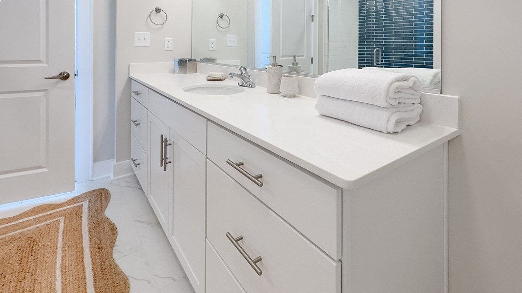 a bathroom with white cabinets and a sink and a mirror