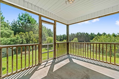 A sunny day on a wooden deck with a view of the trees.