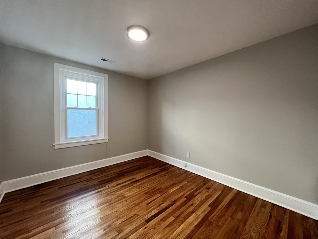 an empty living room with wood floors and a window