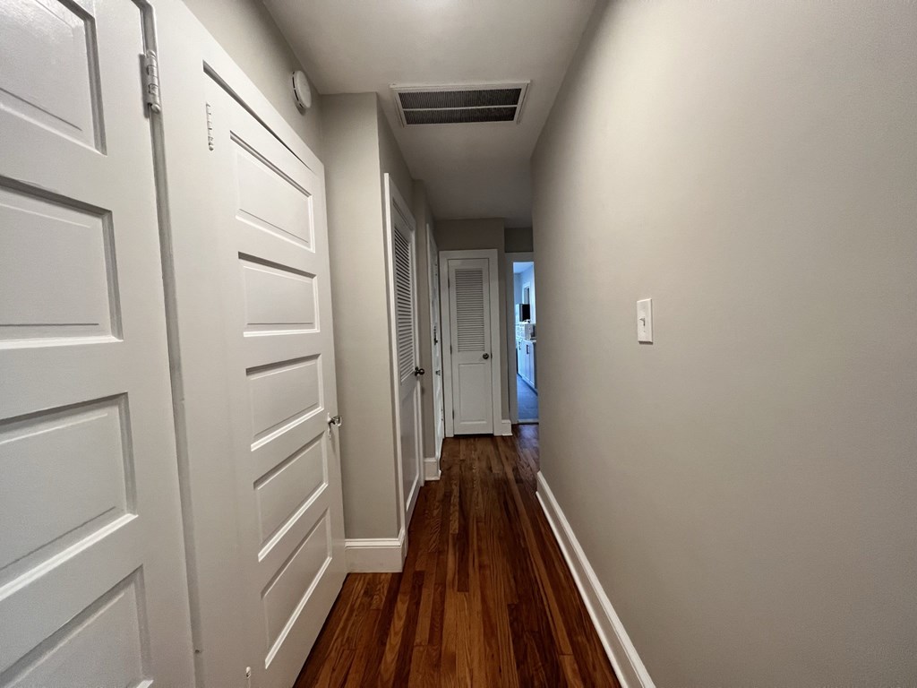 a hallway with white doors and wood floors