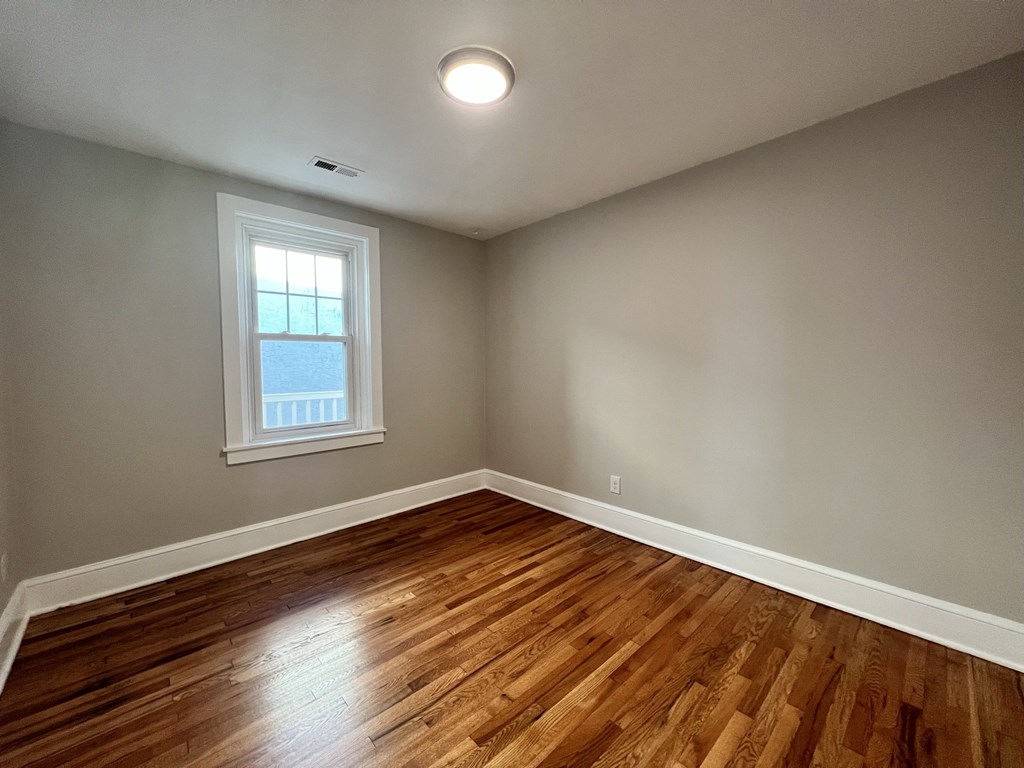 an empty living room with wood floors and a window