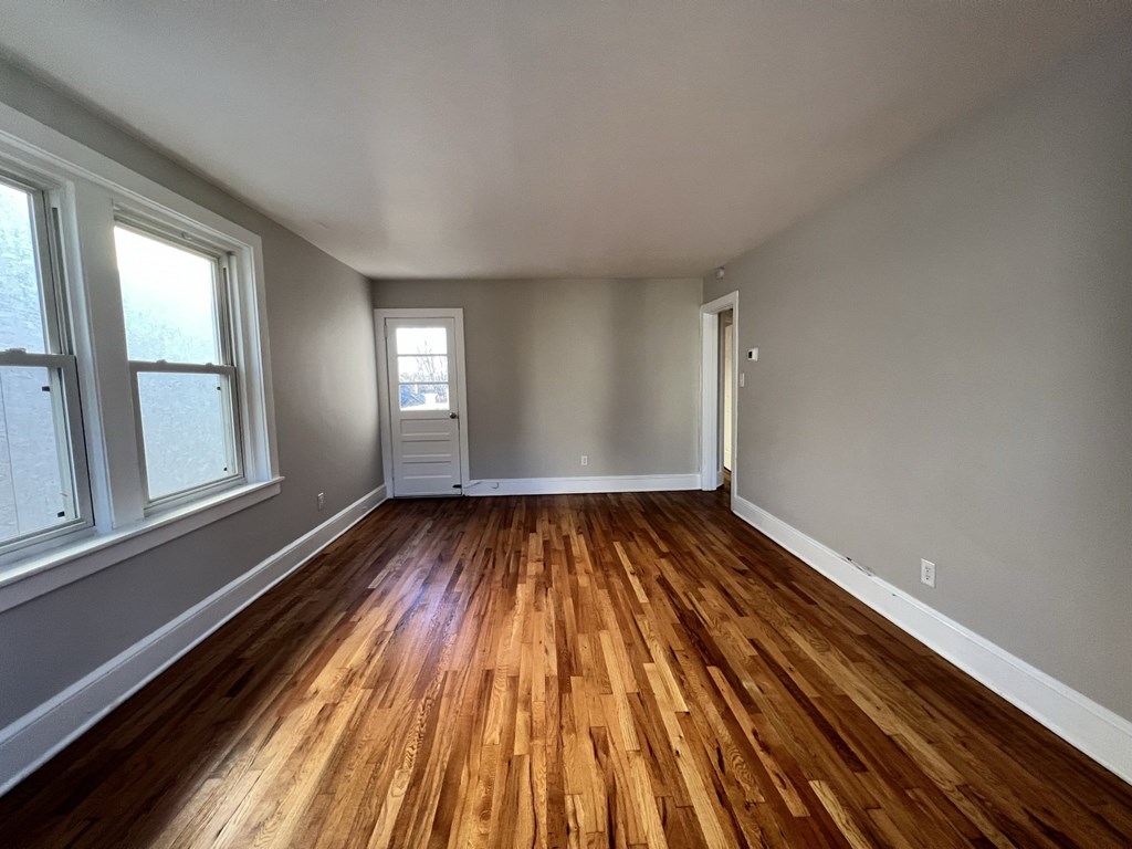 an empty living room with wooden floors and grey walls