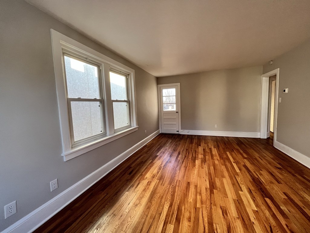 an empty living room with wood floors and large windows