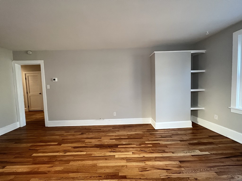 a living room with wood floors and grey walls and shelves