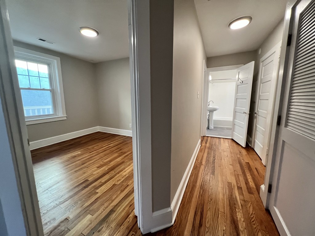 a living room with wood floors and a hallway to a bathroom