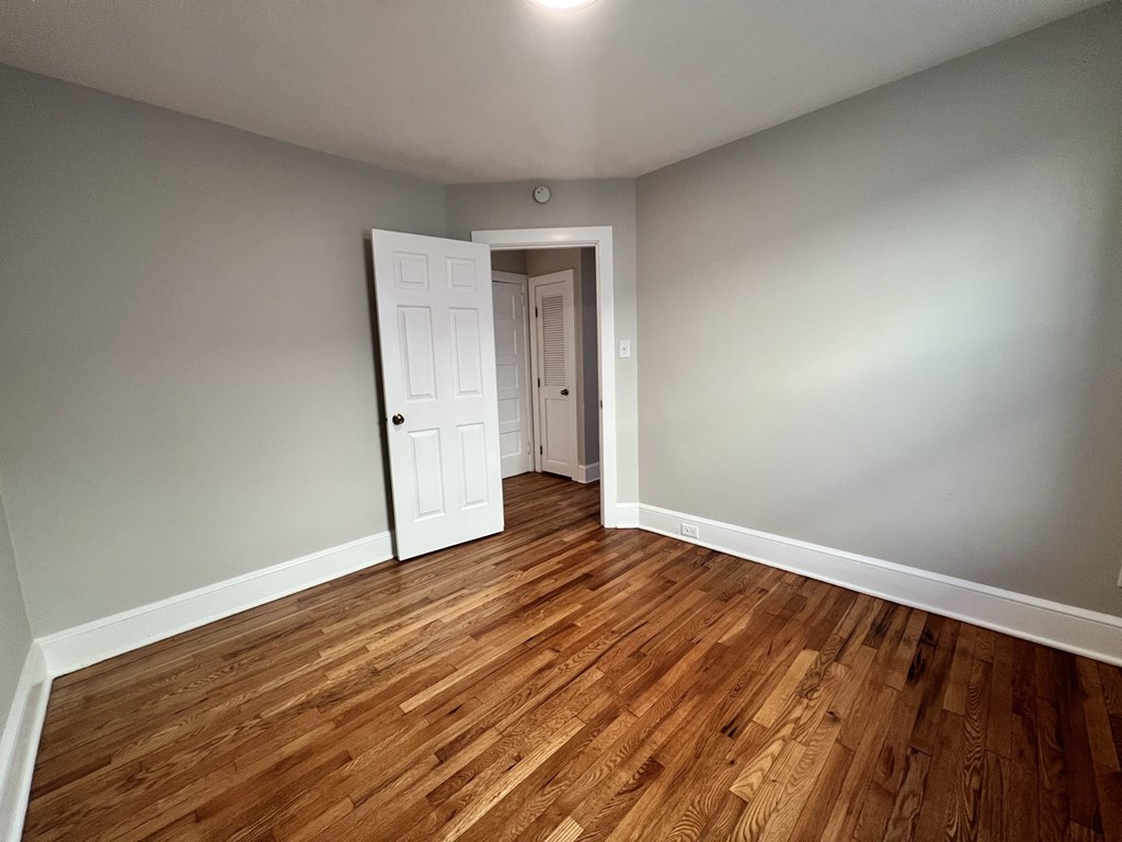 an empty living room with wooden floors and a white door