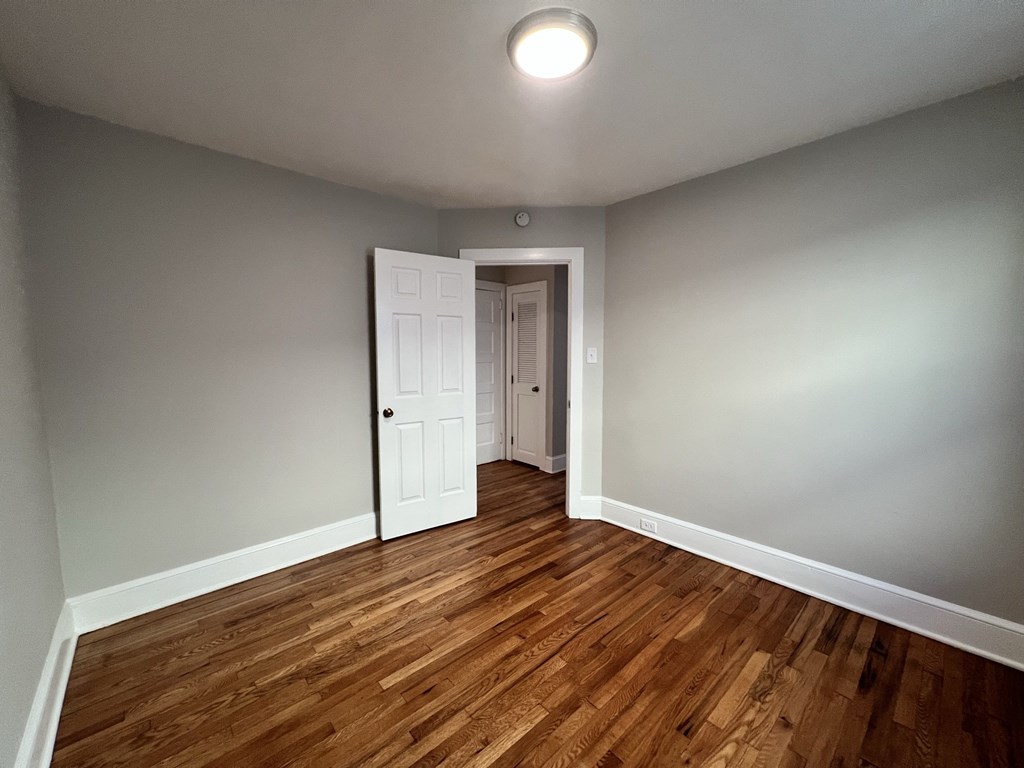 an empty living room with wooden floors and a white door