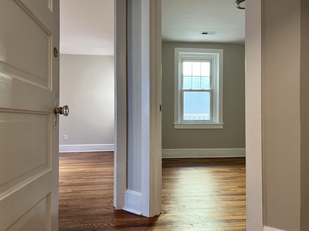 an empty room with wood floors and a window